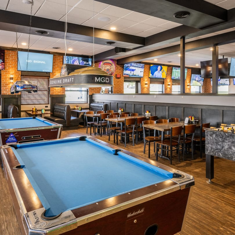 Scores on 33rd's interior with two pool tables, dining tables, booths, and multiple TVs.