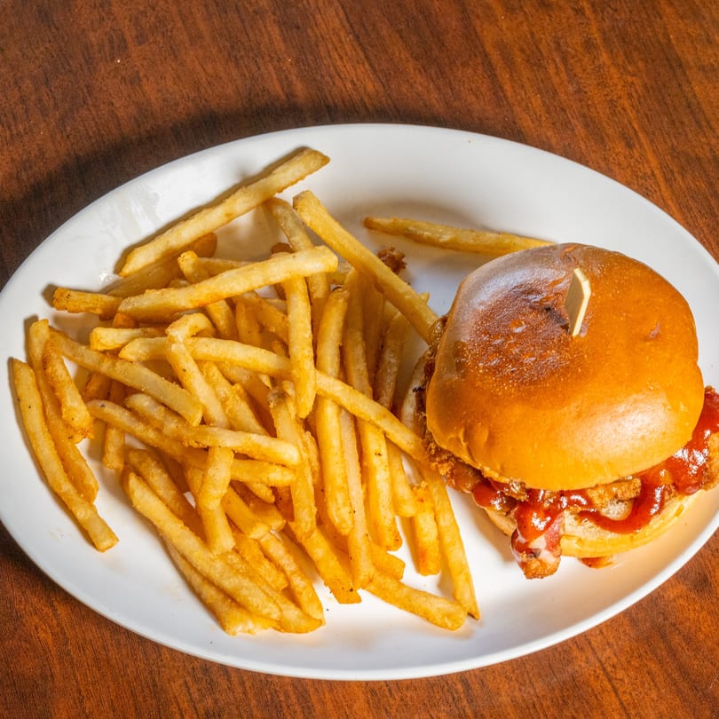 A Scores on 33rd burger with bacon and barbecue sauce, served with a side of fries.